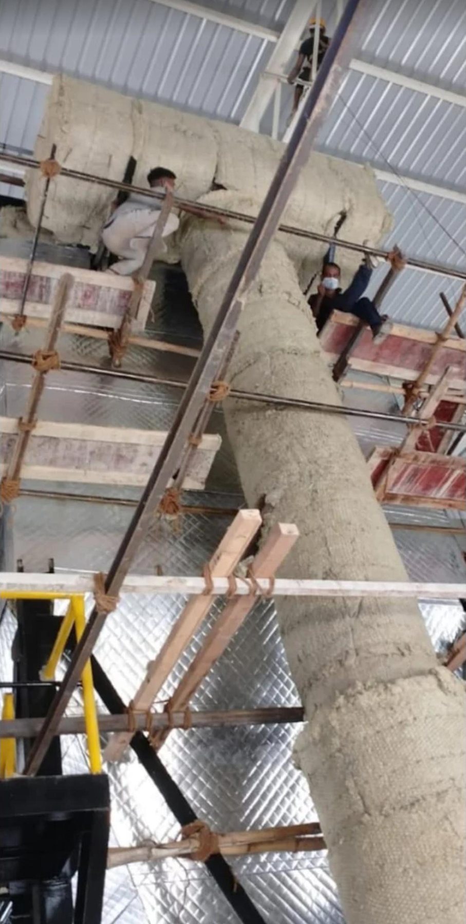 Crew fitting mineral wool insulation on a large duct